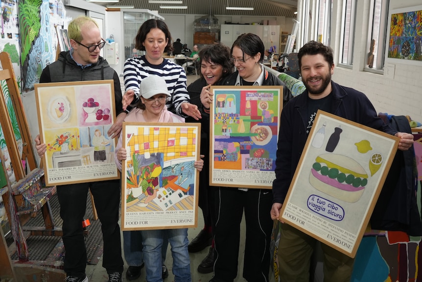 A group of people hold up colorful posters