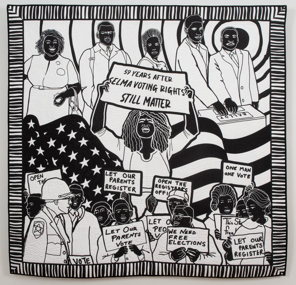 Carolyn Mazloomi Voting Rights. A black and white art quilt loosely divided into three rows. On the top, African Americans line up to cast their vote at the ballot pox. In the center, a Black woman holding a sign reading 