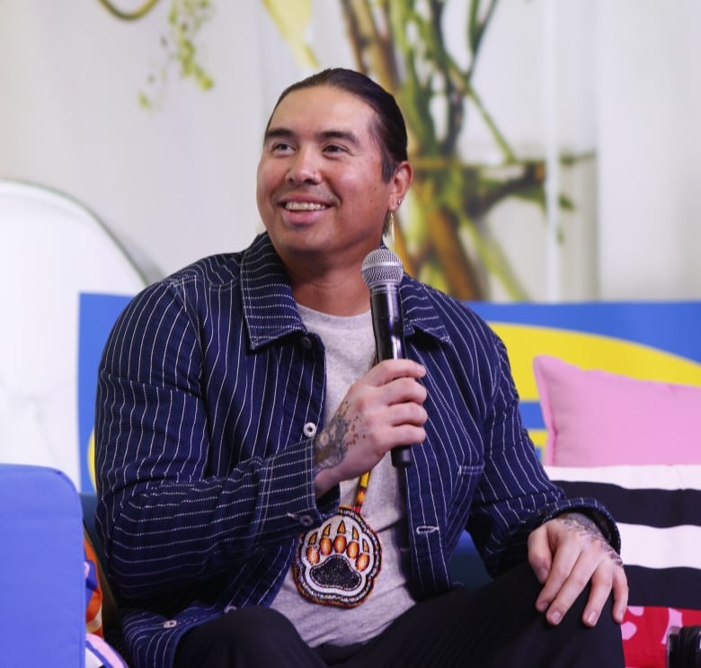 A man with a beaded medallion, smiling. 