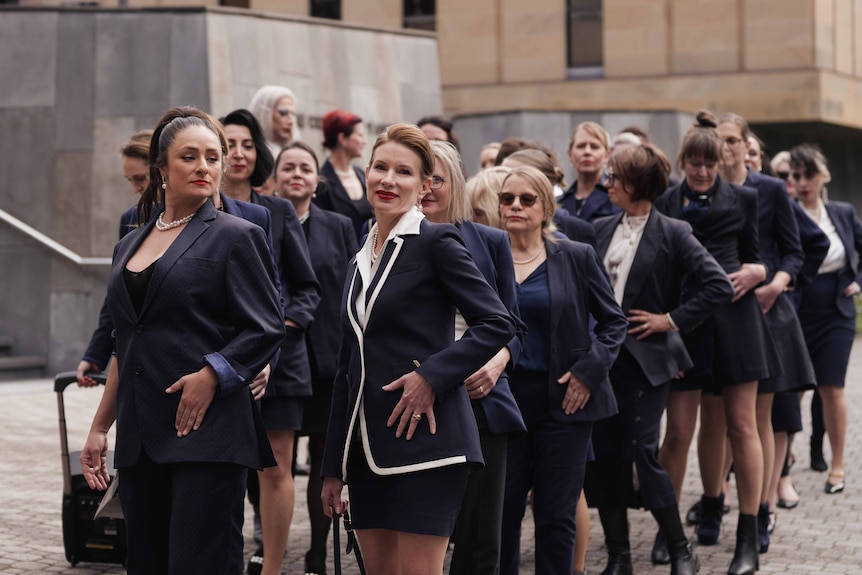 Women in blue suits gathered on the street.