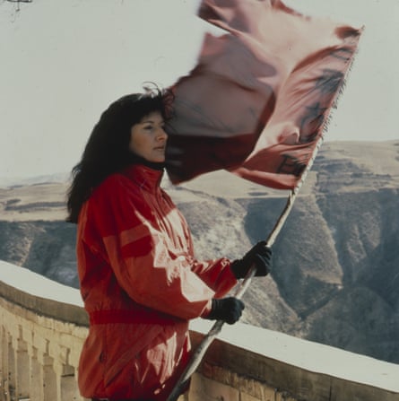 Abramović dressed in red holding flag on Great Wall of China.