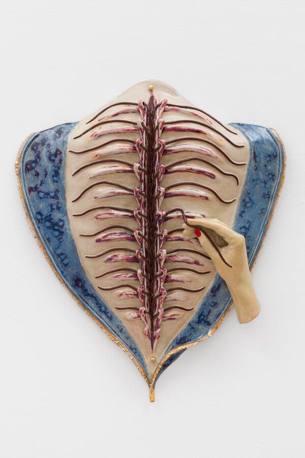 A sculpture of a hand threading veins through an open spine.