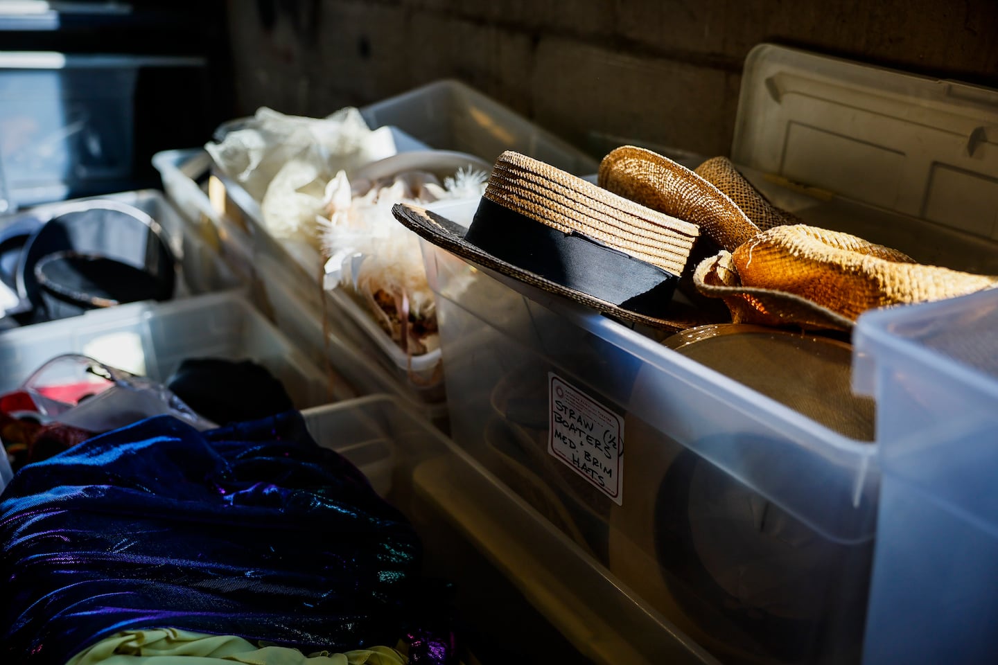 Costume pieces, including straw hats and feathered accessories, fill storage bins at the American Repertory Theater's costume shop sale in Cambridge.