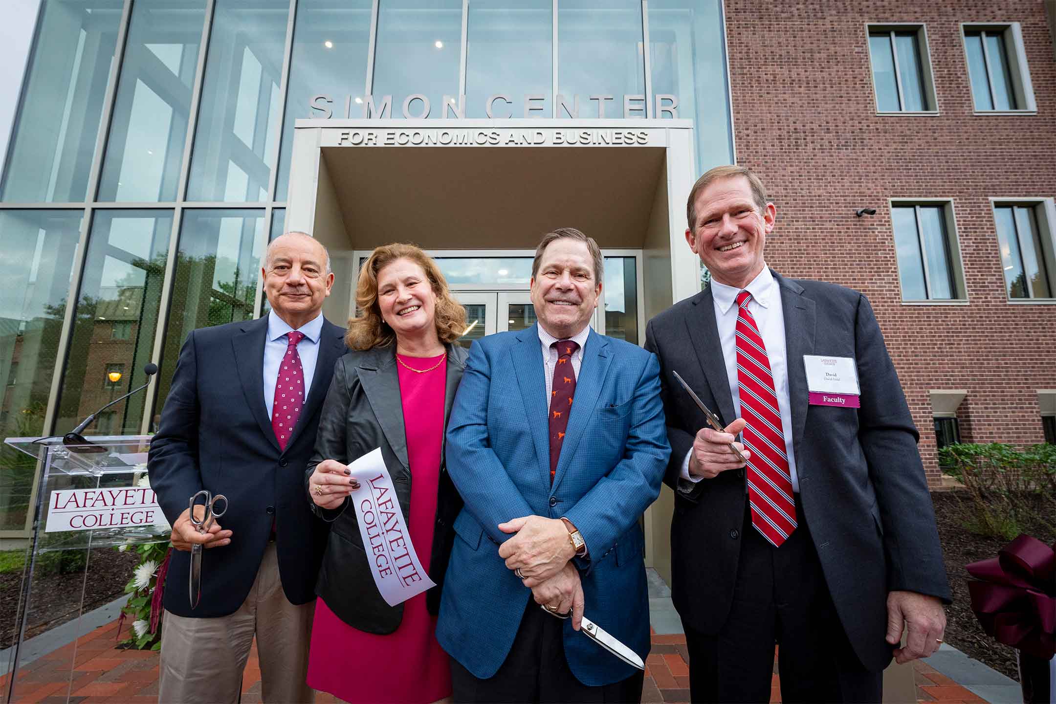 From left: Robert E. Sell ’84, H’18, chair of the Board of Trustees; Nicole Hurd, president, Lafayette College; J. Peter Simon ’75; and David Stifel, Charles A. Dana Professor of Economics Department Head are smiling at the camera after cutting the ribbon in front of the Simon Center.