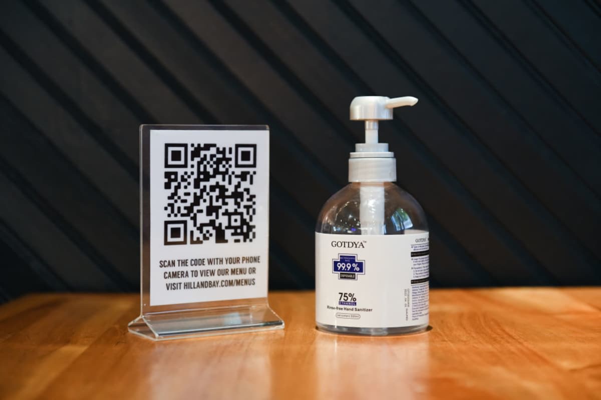 A QR code menu and a bottle of hand sanitizer are placed on a table at Hill and Bay restaurant and bar - (Image source: Noam Galai/Getty Images)