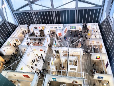 An aerial view of an art fair showing about a dozen booths with several people walking in it.  