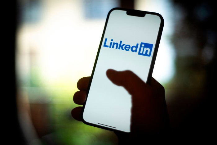 A close-up of a smartphone held in someone’s hand and displaying the LinkedIn logo 