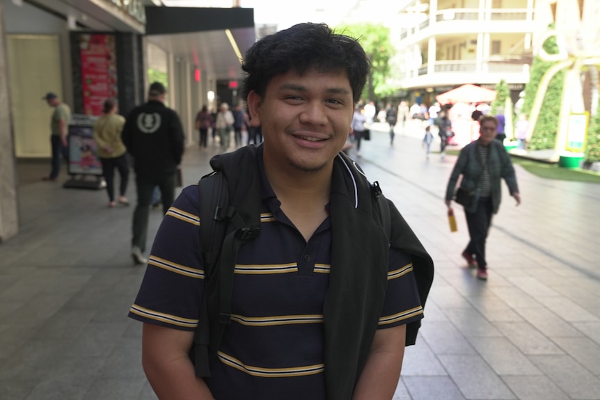 A young man smiles at the camera.