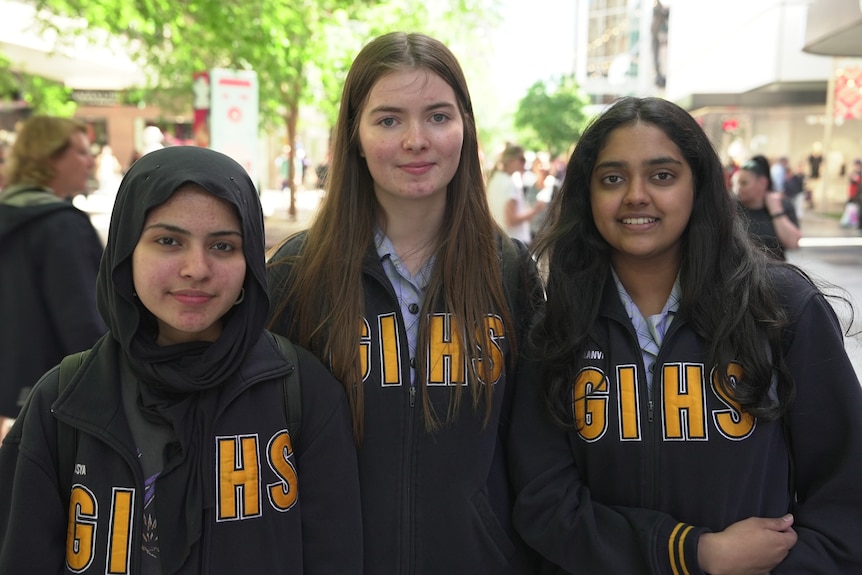 Three teenage girls smile at the camera.