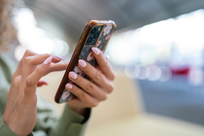 A woman with pretty nails holds a phone