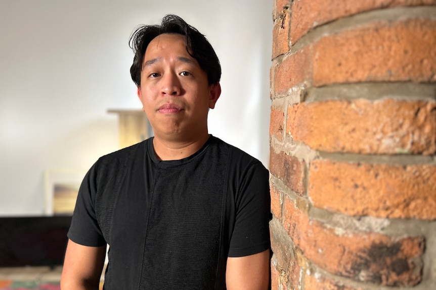 Andrew Kaung leans against a brick wall