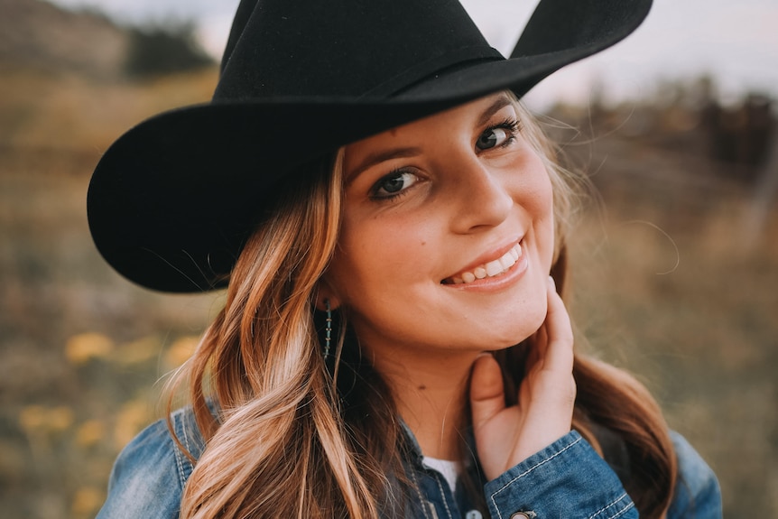 Anna Schott smiles in a portrait photo wearing a cowboy hat