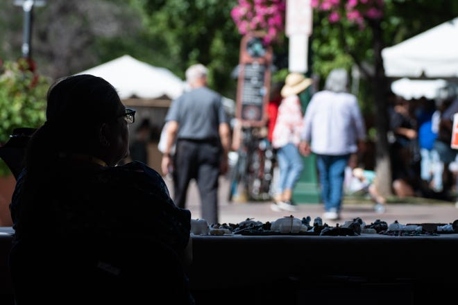 Artist Evalena Boone sits at her booth as people pass by during the Santa Fe Indian Market on Aug. 17, 2024 in Santa Fe, New Mexico.