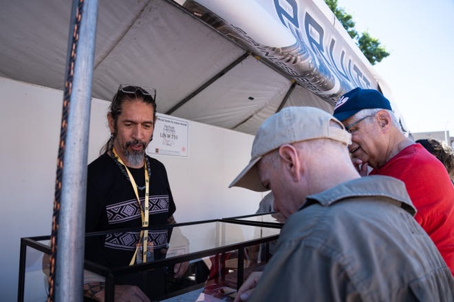 Pat Pruitt (left) helps customers at his booth at the Santa Fe Indian Market on Aug. 17, 2024 in Santa Fe, New Mexico.