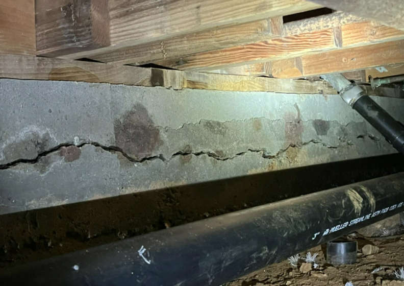 A giant crack running along a slab of concrete underneath a building.
