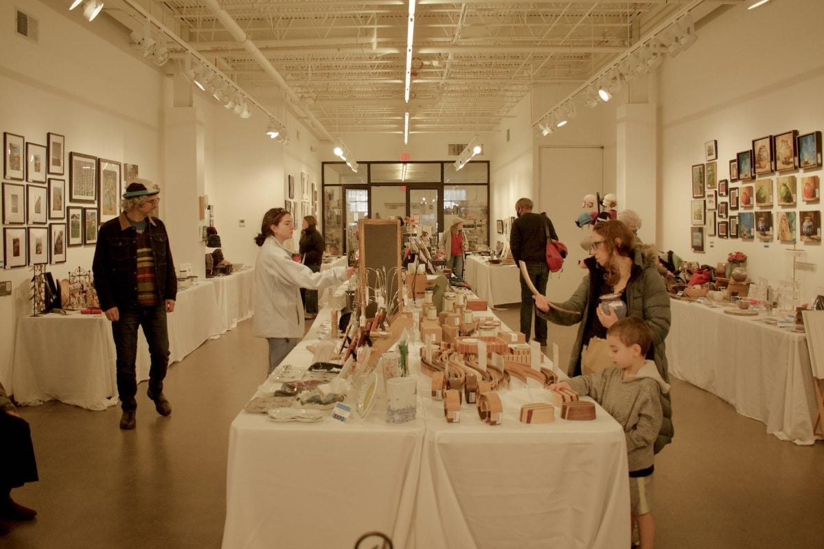 Shoppers browse the aisles of the art show, observing and discussing the art on display.