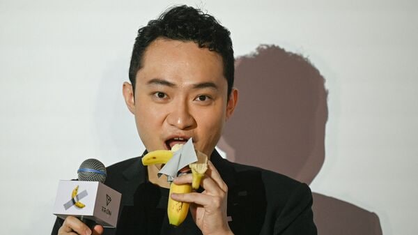 Chinese-born crypto founder Justin Sun eats a banana artwork composed of a fresh banana stuck to a wall with duct tape, in Hong Kong on November 29, 2024, after buying the provocative work of conceptual art by Italian artist Maurizio Cattelan at a New York auction for $6.2 million.