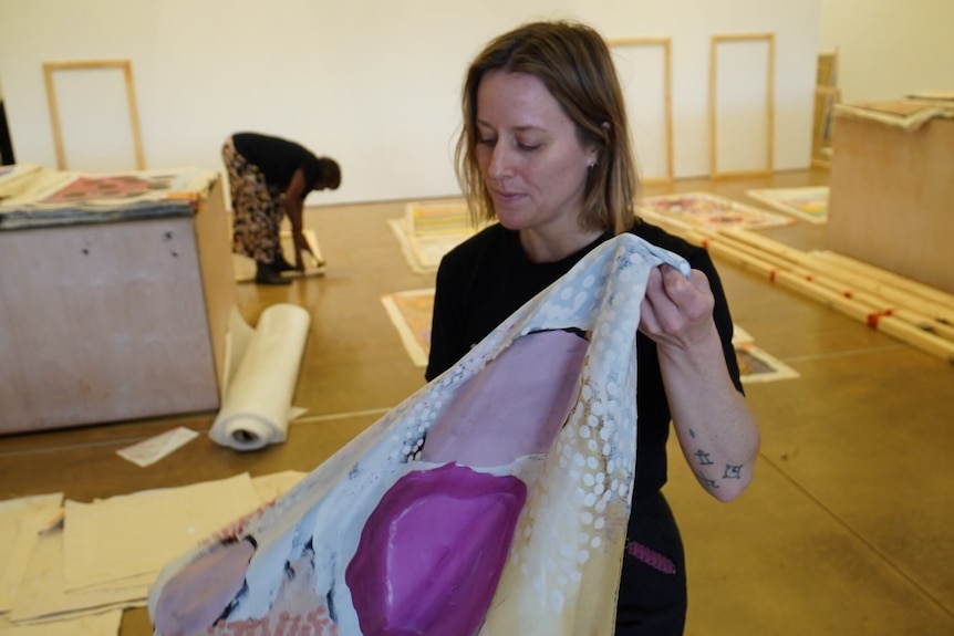 A woman holding a multicoloured scarf