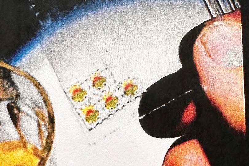Close up of photo on phone with close up on fingers holding acid tabs.