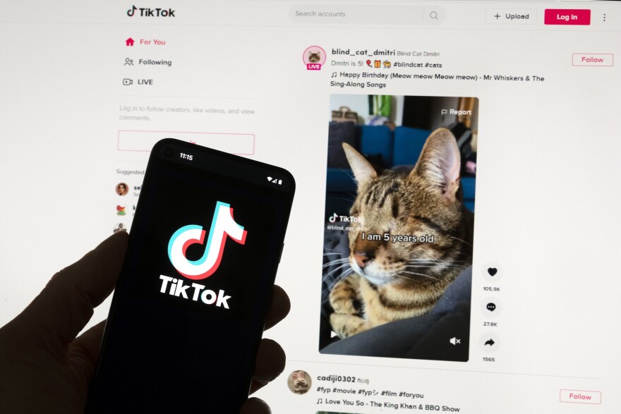 FILE - The TikTok logo is seen on a mobile phone in front of a computer screen which displays the TikTok home screen, Saturday, March 18, 2023. Tech experts are calling Florida’s new social media restriction law a dud. The measure was passed to keep minors off apps like TikTok and Snapchat to protect their mental health.(AP Photo/Michael Dwyer, File)