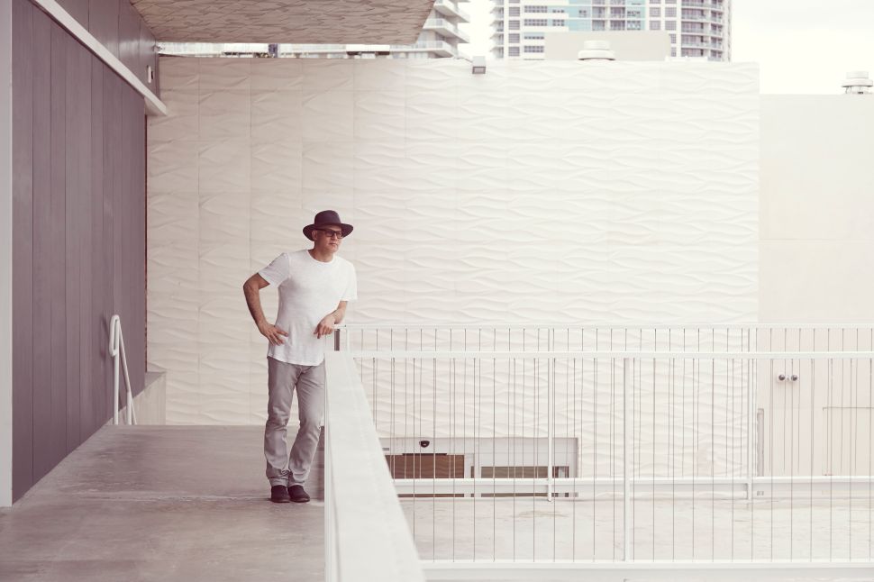 A men dressing in white with a hat inside a modern architecture. 