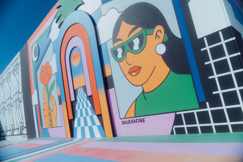 a colorful mural has a female figure in sunglasses and 90s graphic elements