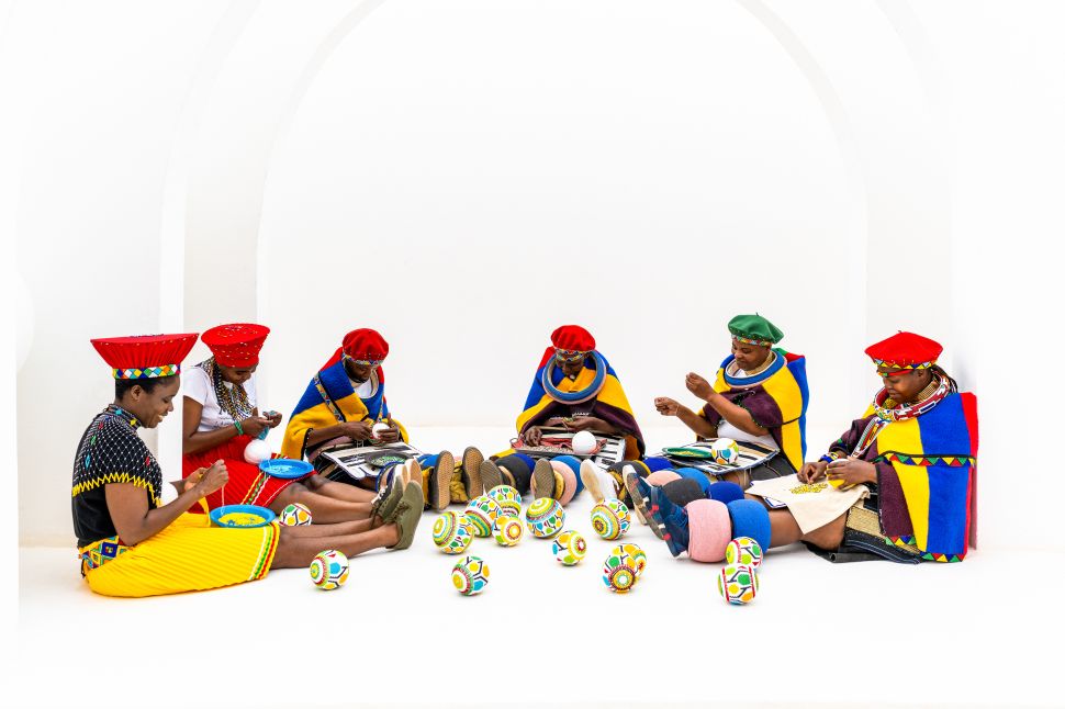 Image of african women in colorful dressses making earings.