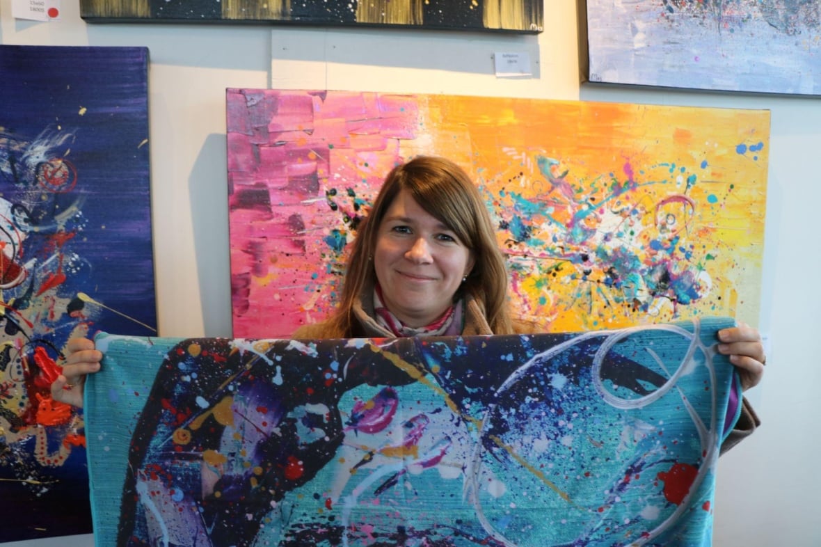 A woman holds up a towel printed with abstract art 