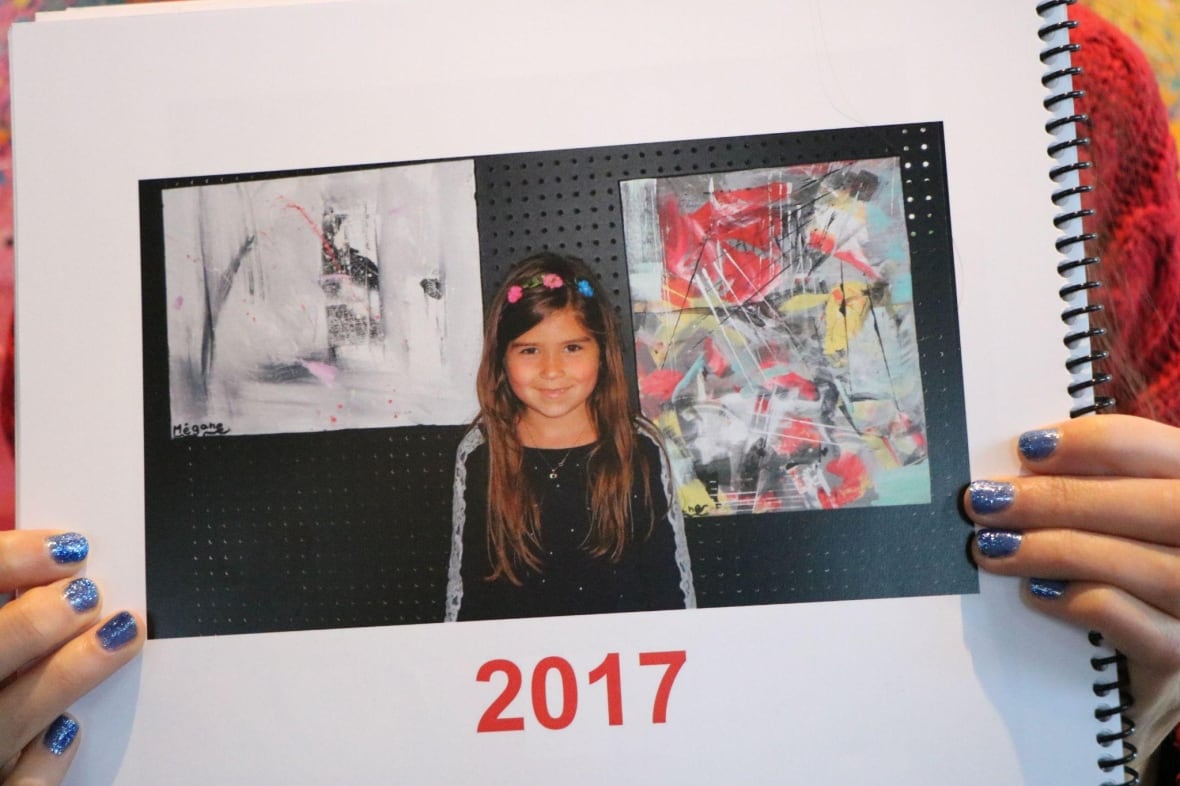 A teen clutches a book displaying a photo of herself when she was a child in 2017.