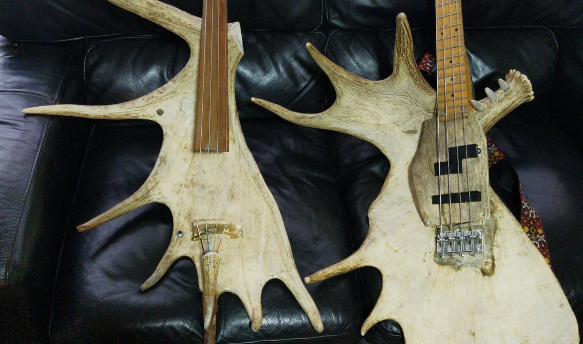 A close up of a guitar made from moose antlers laying on a couch.