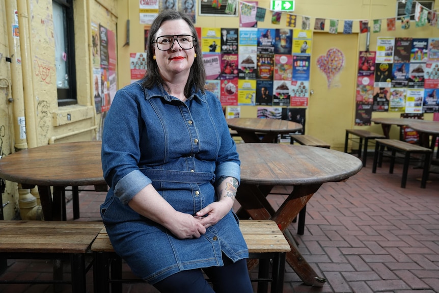 Music SA chief executive Christine Schloithe sits on a table at an Adelaide pub