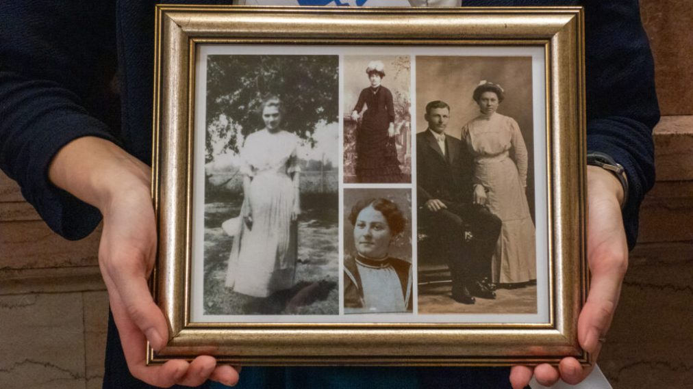 Haley Kelley holds a framed photo of family members Gertrude Charleston Heston, Theresa Balusek and Laura Emma Gray, whose legacy of advocating for women's rights lives on. (Anna Kaminski/Kansas Reflector)