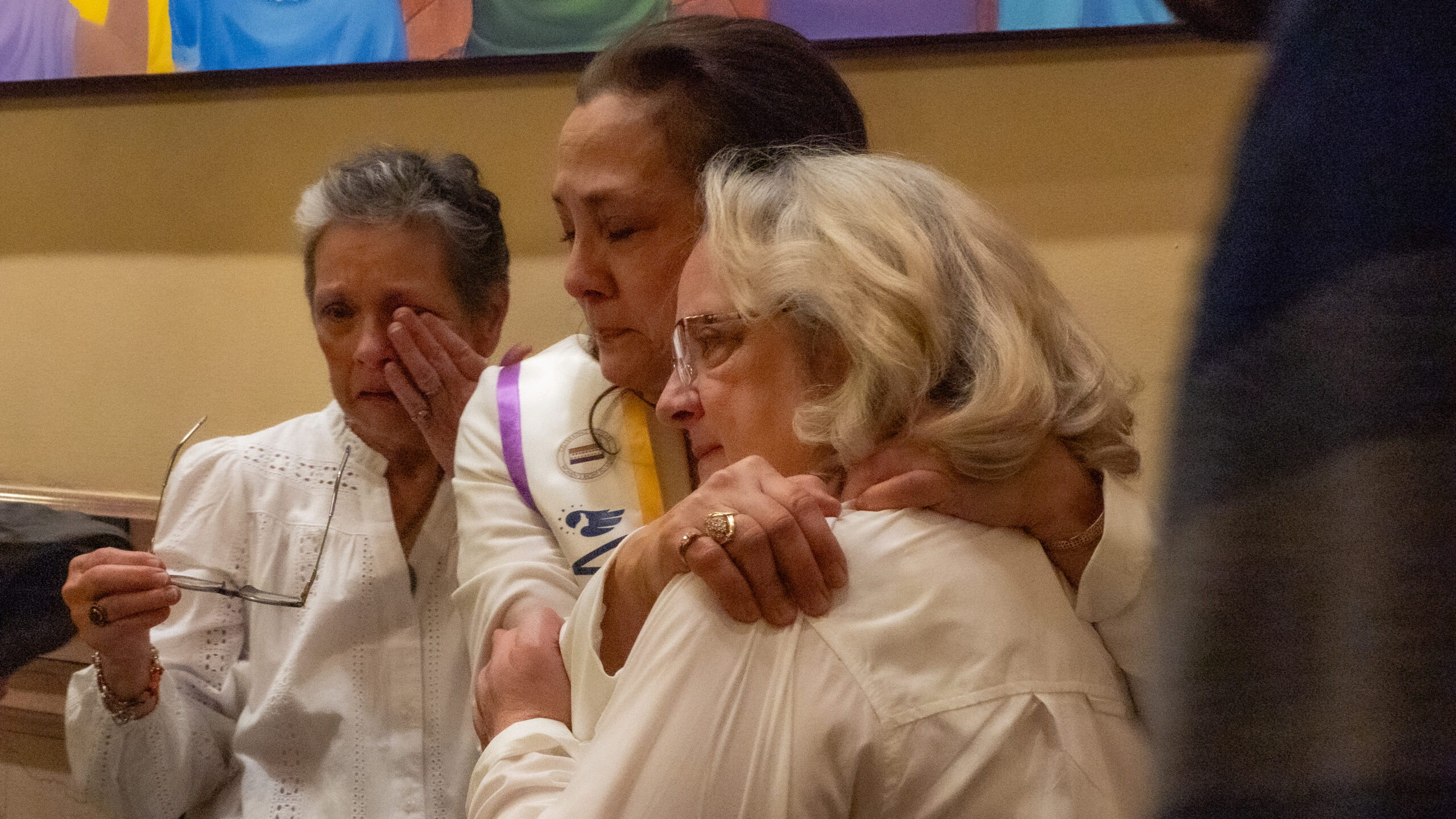 Phyllis Garibay-Coon embraces two of her sisters, Nicki Harders and Jennifer Vulgamore, after the unveiling of her work 