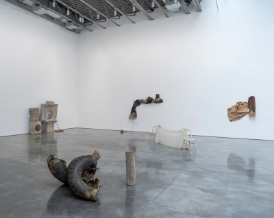 A gallery that contains sculptures composed of broken tires, cardboard elements, and more.