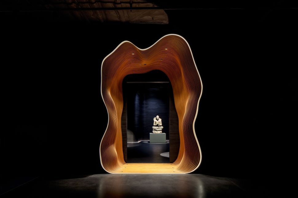 Dark room with a wooden portal and buddha sculptures under the spot lights.