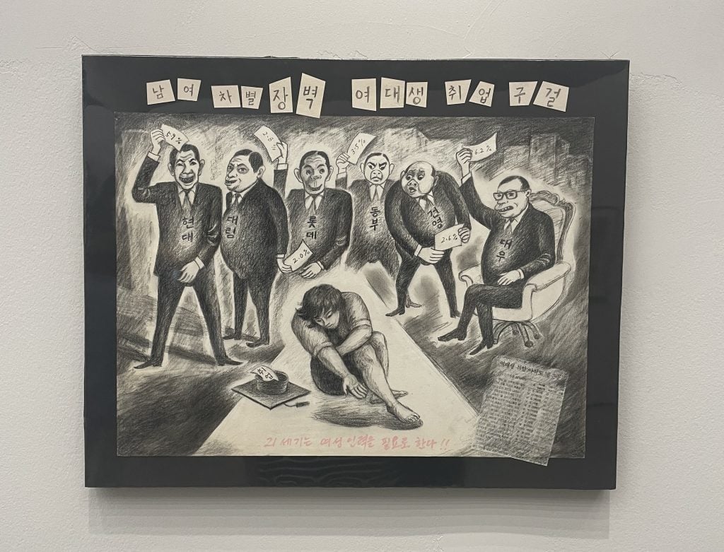 A satirical drawing in black and white featuring a young woman kneeling on the ground, surrounded by a group of older men in suits. The men hold cards with percentages and names, symbolizing societal judgment or discrimination. The text at the top and bottom, written in Korean, emphasizes gender inequality and societal pressures.