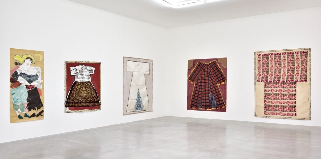 a white walled gallery space with colorful artworks on the wall