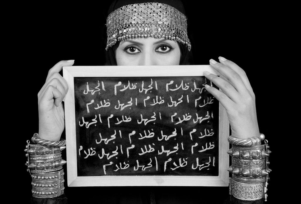 womean holding a chalkboard with arabic writing