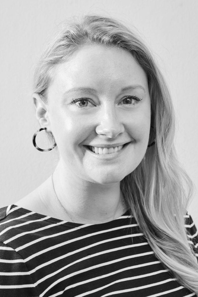 Headshot of a blonde woman posing with hoop earrings and a striped top