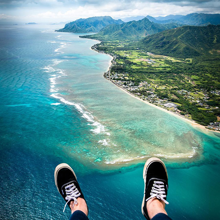 Aerial view over coastline with visible legs, resembling Tom Anderson enjoying a scenic flight.