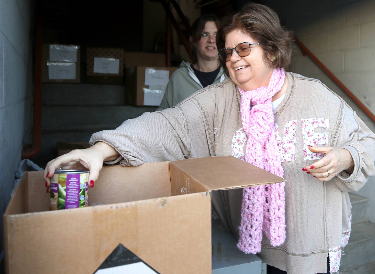 Donna O’Hagan, (front) a Stage Coach Players member, and Angela Schiola, Stage Coach Players community outreach chair, sort donated food into boxes Tuesday, Nov. 12, 2024, at the Stage Coach Theatre in Dekalb. The food collected will be assembled into dinner boxes to provide local families with a Thanksgiving meal.