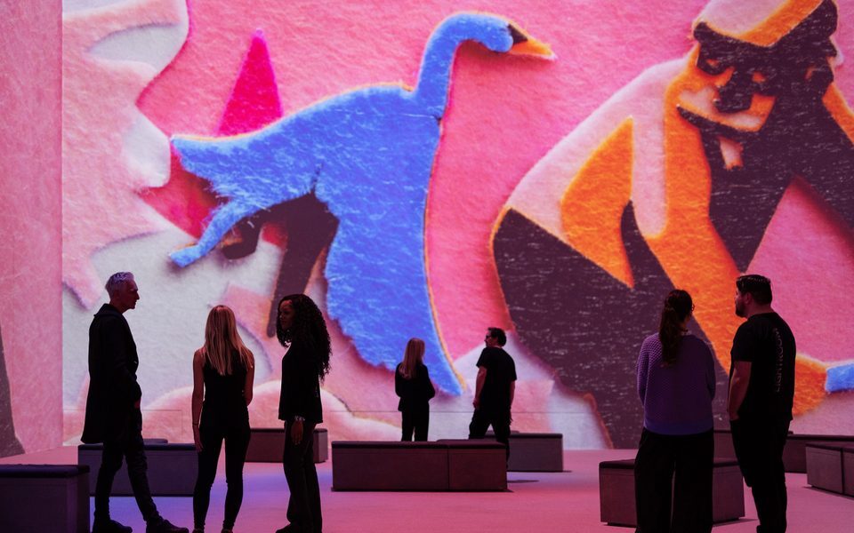 People viewing a large projection of colorful abstract art.