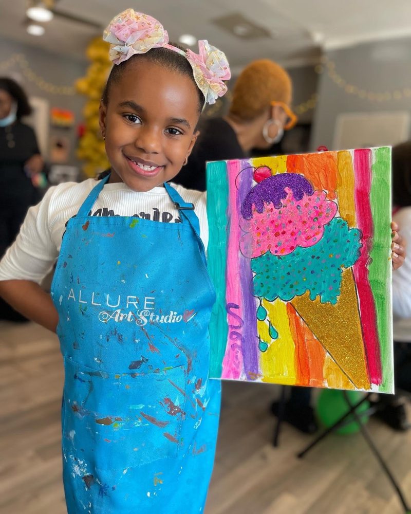 A young girl posing with her painting after attending an event at Allure Studio. (Photo Courtesy of Amy Simon)