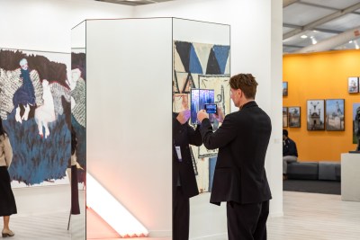 A man takes a photo close up to an artwork with a mirror. 