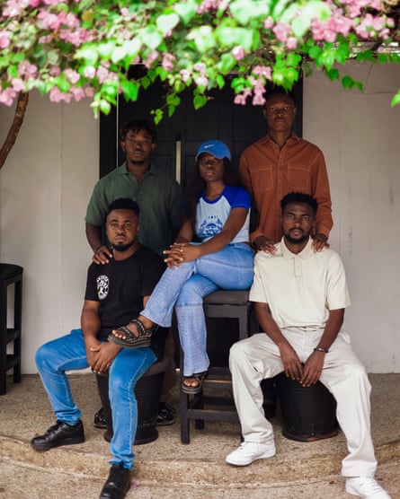 Five people sit on steps beneath a canopy of pink flowers