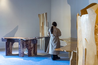 A woman looks at artistic tables at an art fair. 