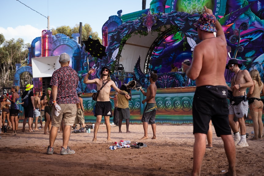 Dancers on a dusty dancefloor with a small pile of rubbish at their feet.