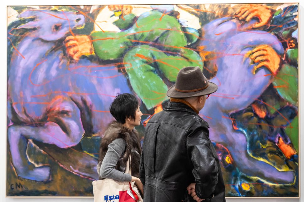 Two asian people looking at a painting. 