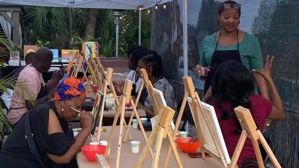 people participating in a painting workshop at an outdoor studio just after sundown 