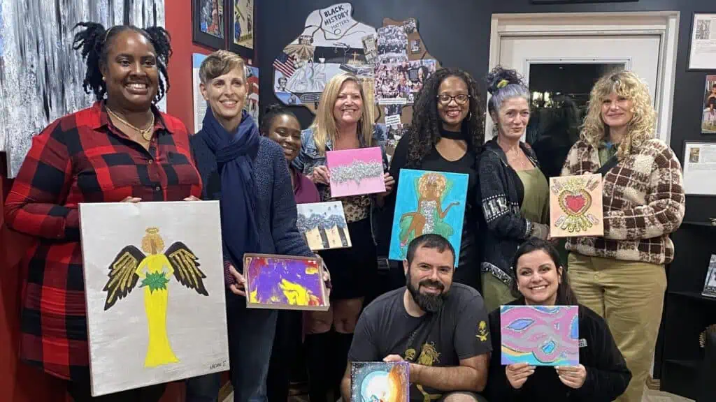 group of people posing with paintings after a workshop